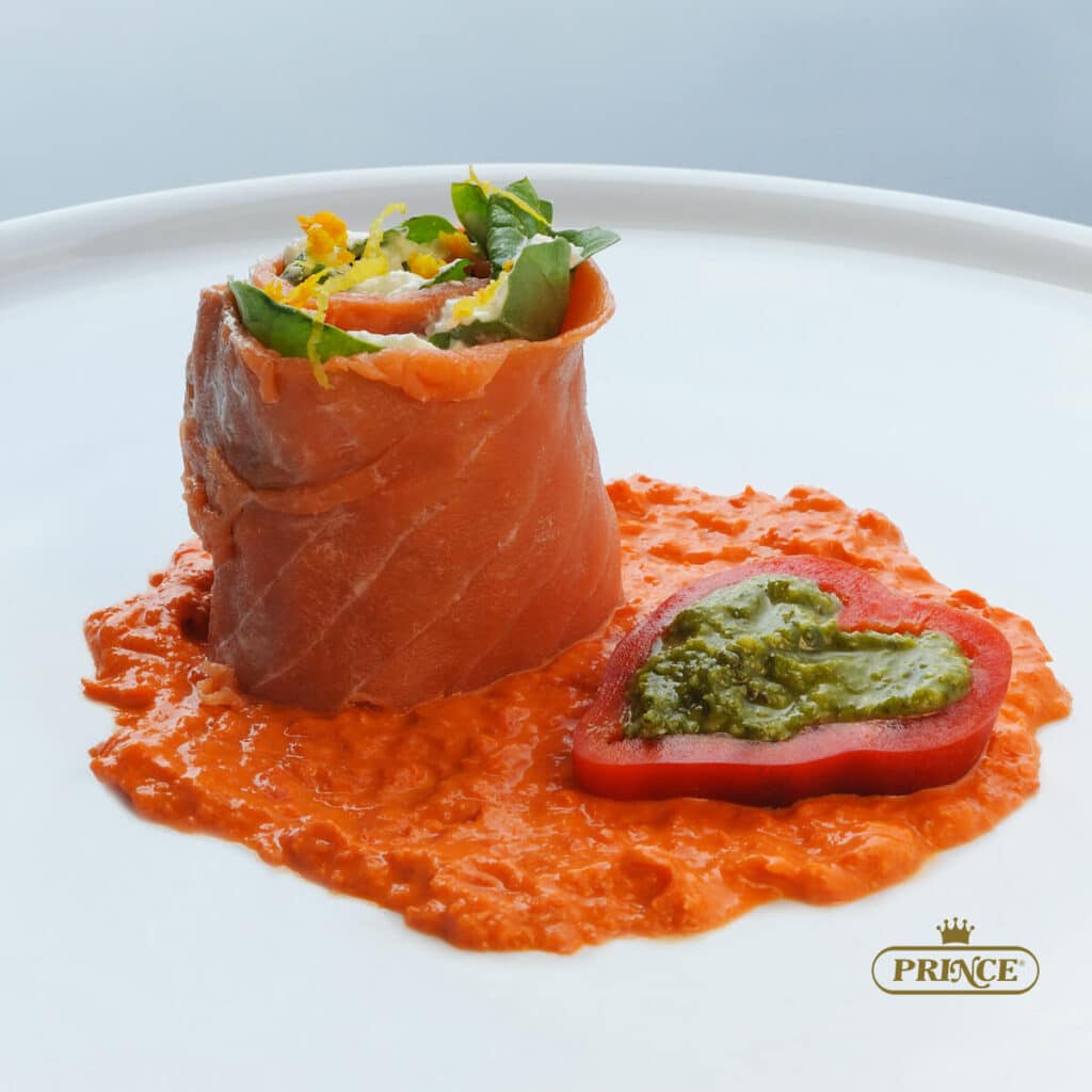 presentazione del rotolo di salmone affumicato con robiola e misticanza su letto di salsa di peperone e pesto di rucola